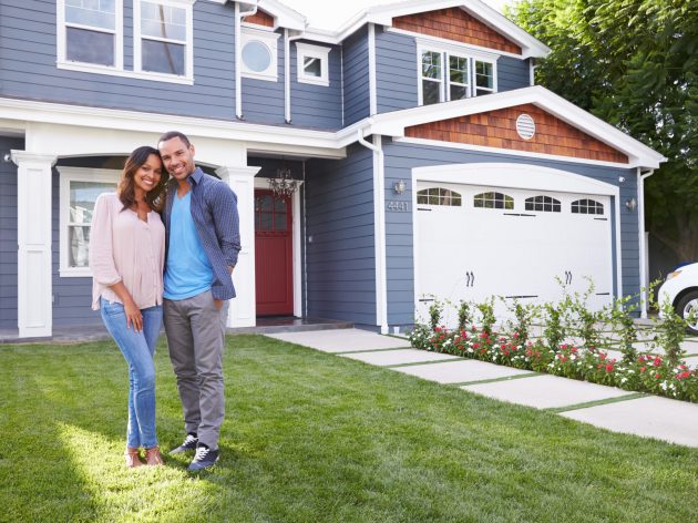 Happy black couple standing outside their house