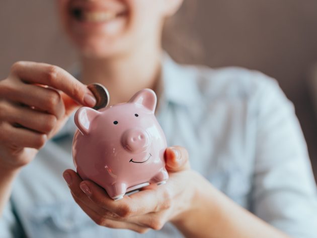 female hands puts a coin in a pink piggy bank. The concept of saving money or savings, investment